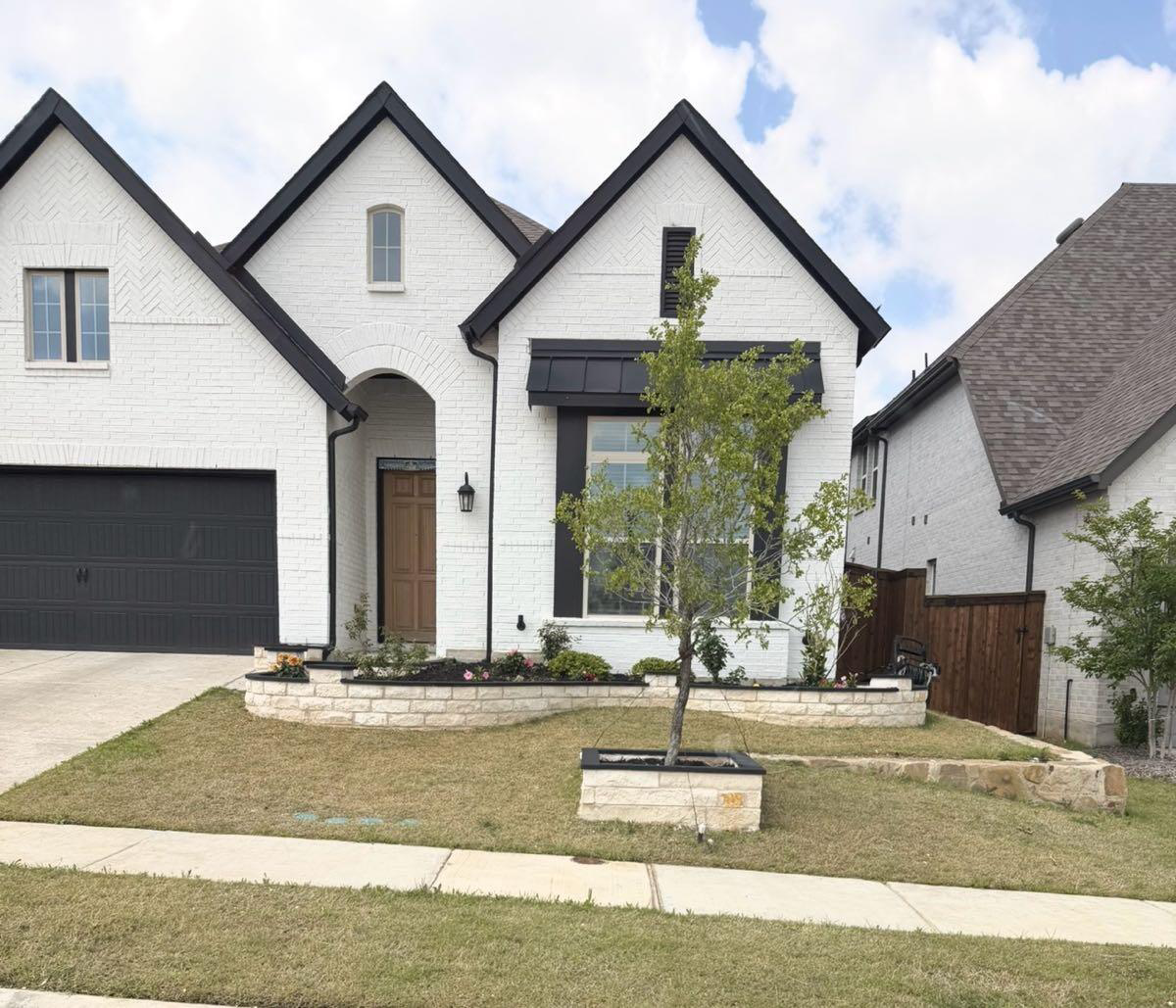 White brick home with fresh sod and stone planter